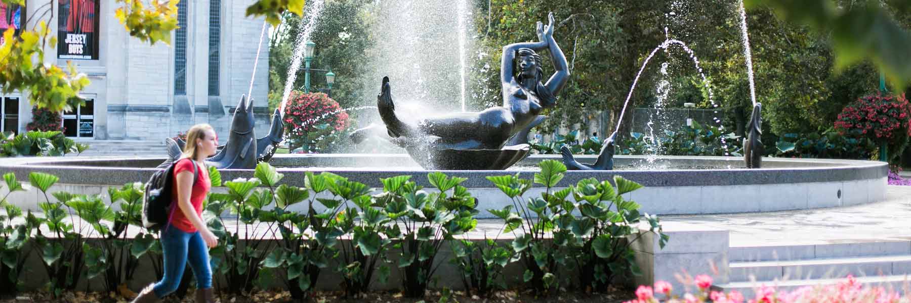 A student passes in front of Showalter Fountain.