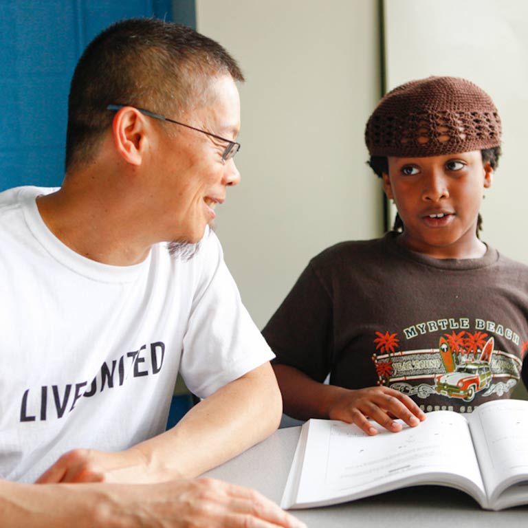 A volunteer tutors a young student.